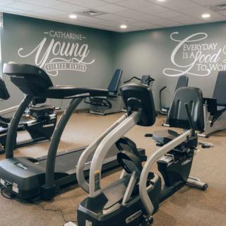 A fitness center equipped with treadmills and elliptical machines, featuring motivational quotes on the walls.