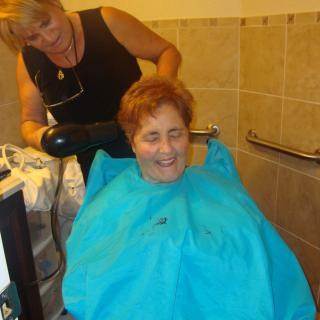A person enjoying a haircut at the salon with a hairdresser.