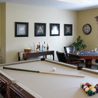 A stylish games room featuring a pool table, bar area, and wall decor.