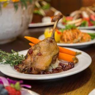 A beautifully plated dish featuring roasted duck with vibrant carrots and fresh herbs.