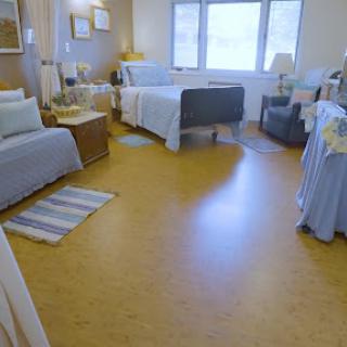 A well-lit hospital patient room featuring a bed, chair, and personal touches for comfort.