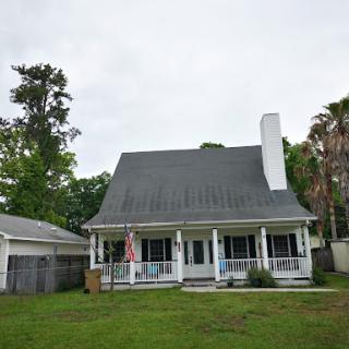 A charming residential house with a welcoming porch and green yard.