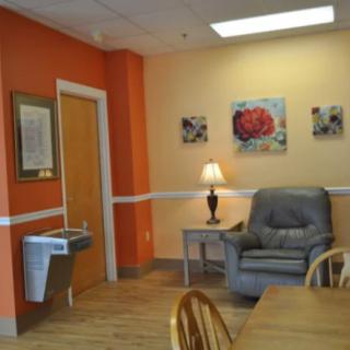 A cozy waiting room with a comfortable chair, table, and artwork on the walls.