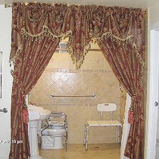 An accessible bathroom with decorative curtains, a sink, and a tiled shower area.