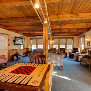 A cozy and rustic living room with a wooden ceiling, comfortable seating, and a game table.