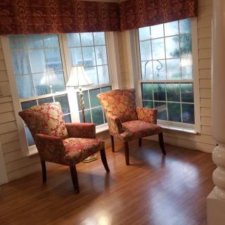 A cozy sitting area with two chairs near large windows and a lamp.