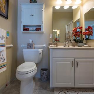 A well-lit bathroom with a toilet, sink, and mirror adorned with decorative elements.