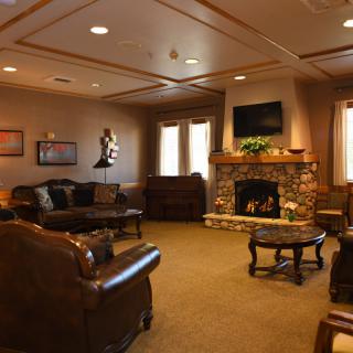 A cozy living room featuring a stone fireplace, leather sofas, and a wall-mounted television.