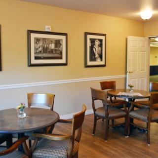 A cozy dining area with wooden tables and chairs, decorated with framed pictures on the walls.