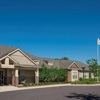 A suburban residential building with a garden and flagpole on a clear day.