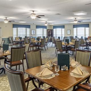 An elegant dining room with neatly arranged tables and chairs, featuring place settings with napkins.