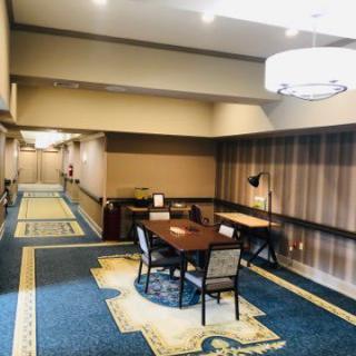 A hotel lobby area with a table, chairs, and elegant carpeted hallway.