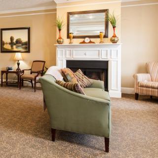 A cozy living room with a fireplace, sofa, and armchair.