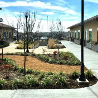 A landscaped courtyard with pathways, lamp posts, and buildings in the background.