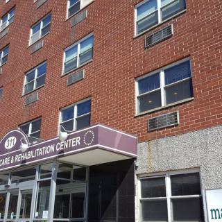 A brick building with multiple windows and an entrance displaying a sign.