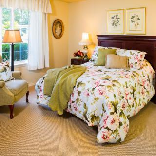 A cozy bedroom with floral bedding and traditional decor.