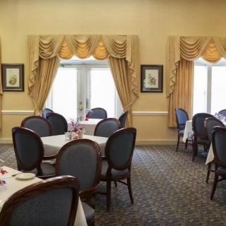 A formal dining room with elegantly set tables and chairs, featuring decorative curtains.