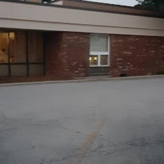 An exterior view of a brick building featuring a large window, taken during the evening.