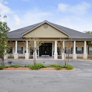 A single-story building with a prominent entrance and surrounding columns, set against a clear sky.
