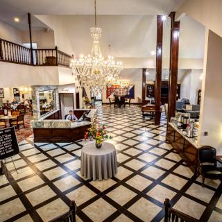 A spacious and elegant hotel lobby featuring a large chandelier and stylish furniture.