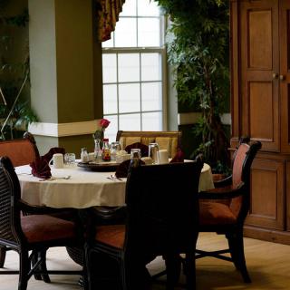 A beautifully set dining table in an elegant and cozy room with a large window.