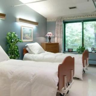 A clean hospital room with two beds and a large window.