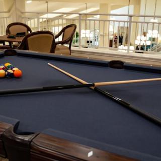 A cozy game room with a pool table set up for play, complete with cue sticks and billiard balls.