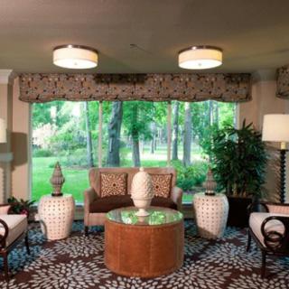 A cozy living room with elegant furniture and a large window providing a scenic view of the greenery outside.