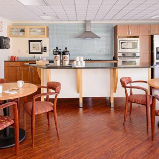 A modern kitchen and dining area with wooden flooring, featuring a coffee station and appliances.