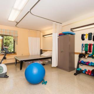 A well-equipped therapy room featuring exercise equipment like a blue exercise ball and weights, ideal for rehabilitation sessions.