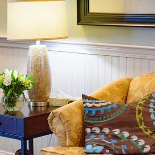 A cozy living room corner featuring a stylish sofa, decorative pillows, a touch of greenery, and ambient lighting.