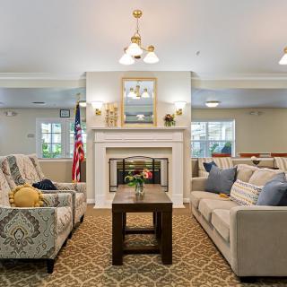 A cozy living room featuring a central fireplace, two sofas, and a wooden coffee table, adorned with comfortable decor and ambient lighting.