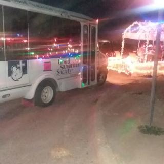 A vehicle adorned with colorful lights parked during an evening event.