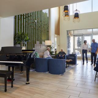 A spacious lobby area features a grand piano, modern seating, and contemporary decor.