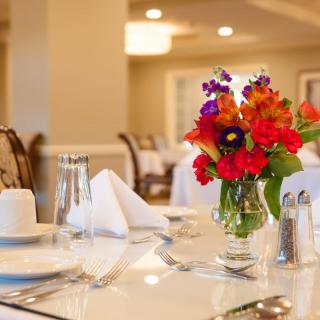 A beautifully set dining table with vibrant flowers in an elegant restaurant setting.