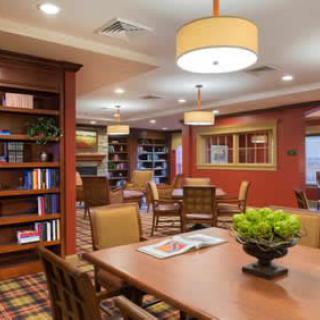 A cozy library interior with bookshelves, tables, and chairs arranged for reading and study.