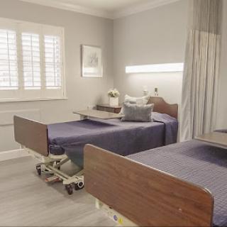 A modern patient room featuring two hospital beds and a serene interior atmosphere.