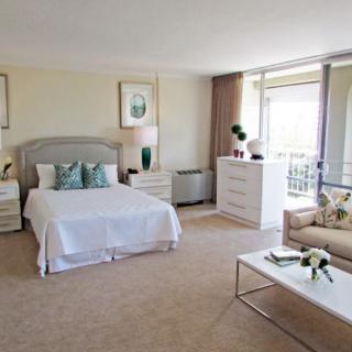 A modern and bright bedroom with elegant decor, featuring a comfortable bed, stylish furniture, and a large window.