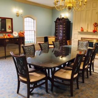 A classic dining room with a polished table, elegant chairs, and a chandelier overhead.