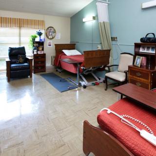 A well-organized nursing home room with beds and furniture for patient care.