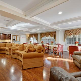 A spacious and elegantly furnished living room with a dining area, featuring comfortable couches and wooden flooring.