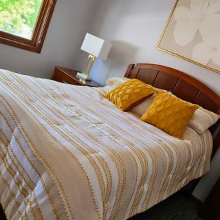 A cozy and inviting bedroom featuring a neatly made bed with striped bedding and yellow decorative pillows.