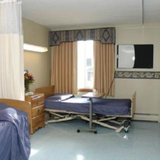 A hospital room with a medical bed and curtains near a window.