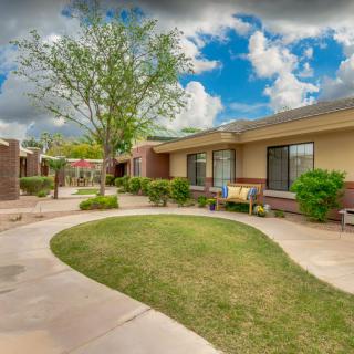 A beautifully landscaped courtyard featuring a tree and grass, surrounded by buildings under a cloudy sky.