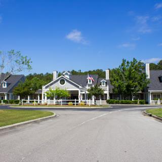 A serene residential building surrounded by greenery and a clear blue sky.