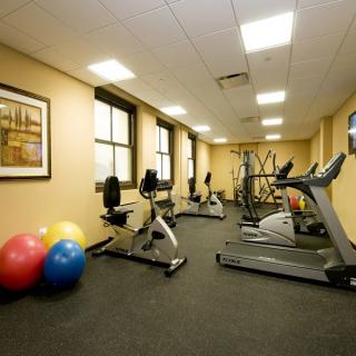 A small indoor gym with exercise equipment including treadmills, stationary bikes, and fitness balls.