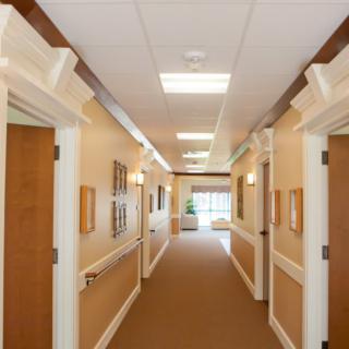 A well-lit hallway with multiple doors and framed pictures on the walls.