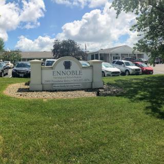 A view of a building with a prominent sign in a well-maintained outdoor area, surrounded by parked cars.