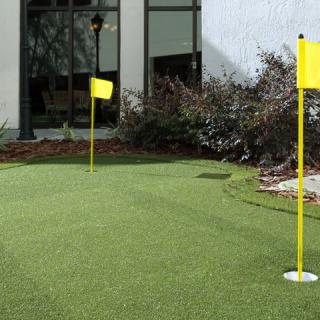 A small outdoor putting green with yellow flags on artificial turf.