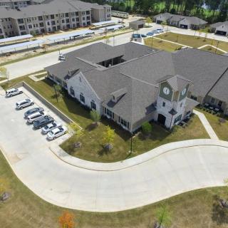 Aerial view of a residential building with surrounding parking lot and landscaped areas.